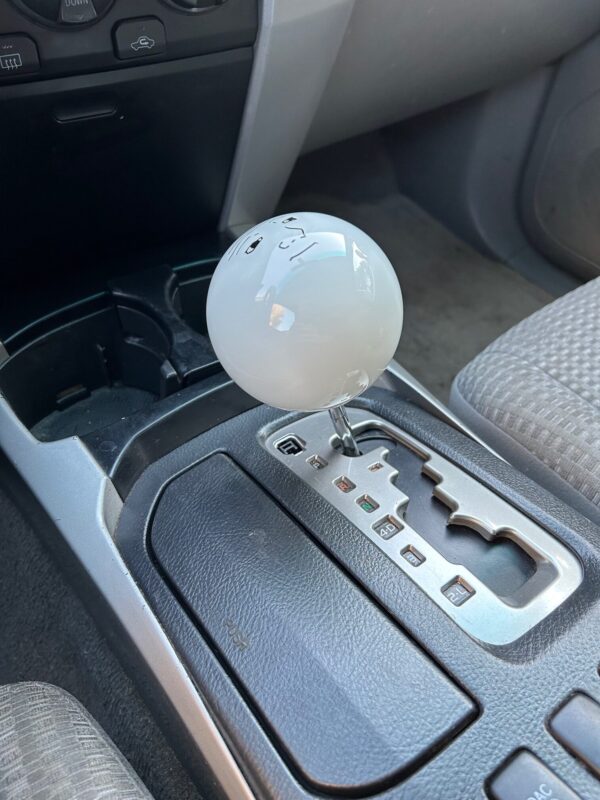 Very large white shift knob installed in a Toyota 4Runner with an automatic transmission.
